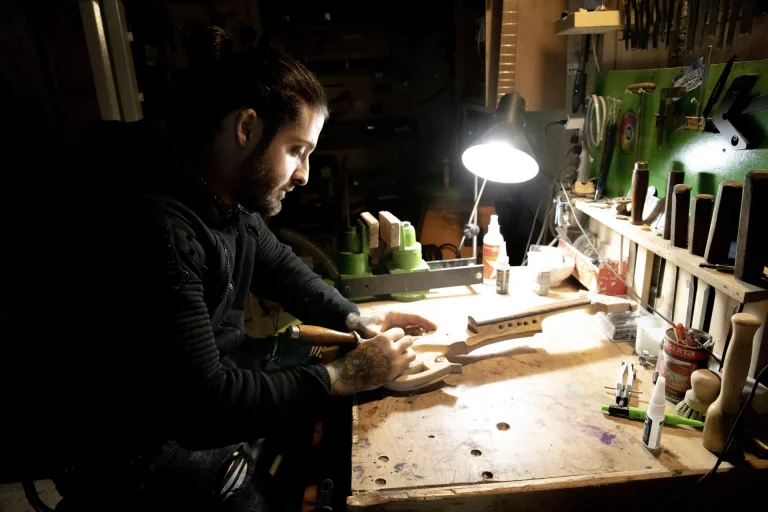 benjamin midejean sacrilegious designs working on a workbench with dim light